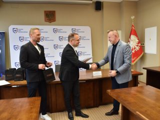 Uczestnik w jasnoniebieskiej marynarce przyjmuje gratulacje i certyfikat KGHM.
