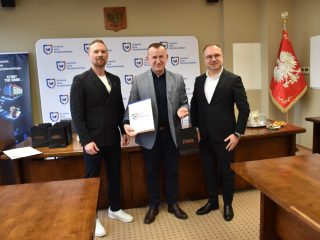 Wyróżniony z certyfikatem pozuje pomiędzy dwoma przedstawicielami podczas uroczystości KGHM.