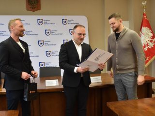 Odczytywanie certyfikatu dla uczestnika w szarym swetrze.