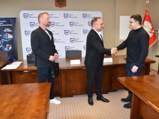 Uczestnik w czarnej koszuli przyjmuje gratulacje podczas wręczenia certyfikatów KGHM.