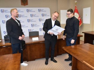 Odczytywanie certyfikatu dla uczestnika w okularach i czarnej koszuli.