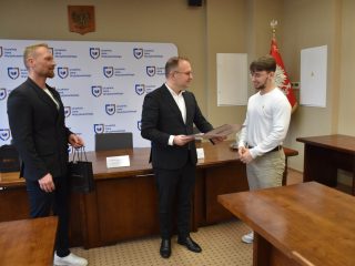 Odczytywanie certyfikatu dla uczestnika w białej koszulce.
