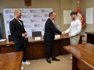 Uczestnik w białej koszulce przyjmuje gratulacje podczas uroczystości KGHM.
