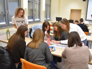 Uczestniczki wspólnie zapisują odpowiedzi na kartach pracy przy ławkach.