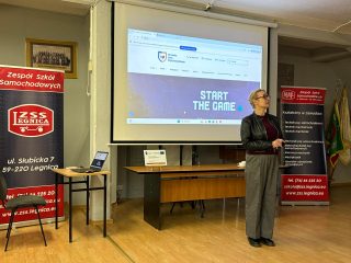 Przedstawicielka UJW stoi przy ekranie wyświetlającym stronę uczelni.