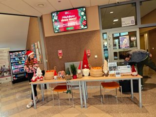 Świąteczne stoisko w holu UJW z ozdobami, koszami i materiałami informacyjnymi.
