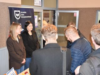 Przedstawicielki CCC rozmawiają z grupą młodych mężczyzn w holu UJW.