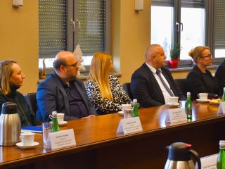 Uczestnicy Rady Dyrektorów siedzą przy stole z wizytówkami i materiałami spotkania.
