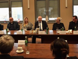 Widok uczestników Rady Dyrektorów po obu stronach stołu konferencyjnego.