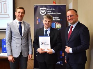 Mężczyzna w ciemnym garniturze trzyma dokument podczas wspólnego zdjęcia na spotkaniu Rady Dyrektorów.