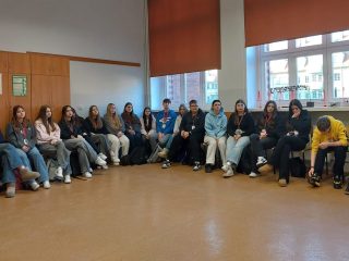 Uczniowie siedzą w kręgu pod oknami podczas warsztatów Chłopskiej Szkoły Biznesu.