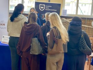 Grupa uczennic przy stoisku UJW na targach edukacyjnych w Głogowie.