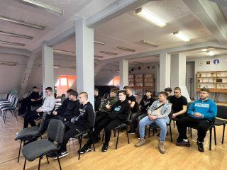 Uczniowie siedzą w rzędach krzeseł podczas spotkania z przedstawicielką UJW.