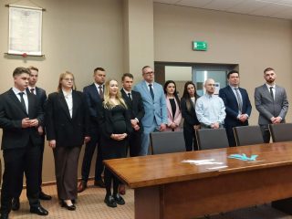 Uczestnicy obron inżynierskich stoją w sali przy długim stole.