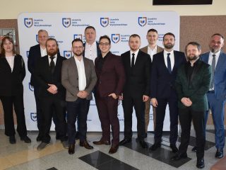 Uczestnicy obron na kierunkach inżynierskich pozują na tle ścianki z logo UJW.