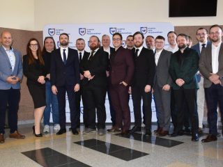 Liczna grupa uczestników obron inżynierskich pozuje wspólnie przy ściance UJW.