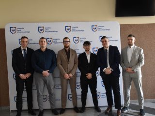 Sześciu absolwentów kierunków inżynierskich pozuje przy ściance z logo UJW.