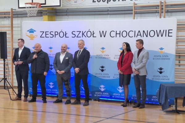 Przemówienie przedstawicieli instytucji na tle planszy Zespołu Szkół w Chocianowie.
