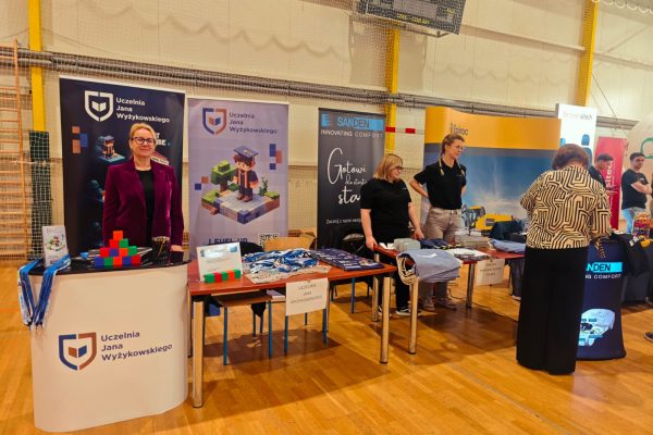 Stoisko UJW z materiałami promocyjnymi w hali targów edukacyjnych.