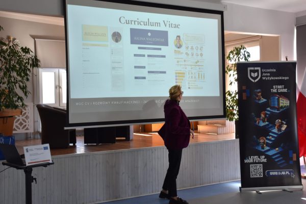 Prowadząca omawia slajd o curriculum vitae podczas spotkania z uczniami.
