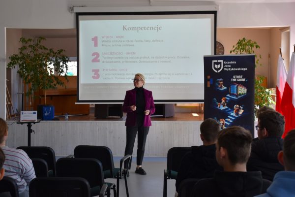 Prowadząca prezentuje temat kompetencji uczniom siedzącym w sali.