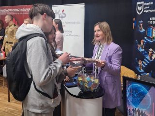 Odwiedzający oglądają materiały przekazywane przez przedstawicielkę UJW na targach pracy.
