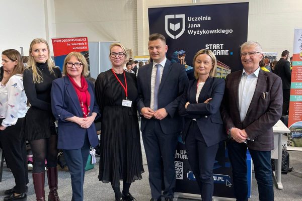 Przedstawiciele instytucji pozują przy stoisku UJW na targach edukacyjnych.