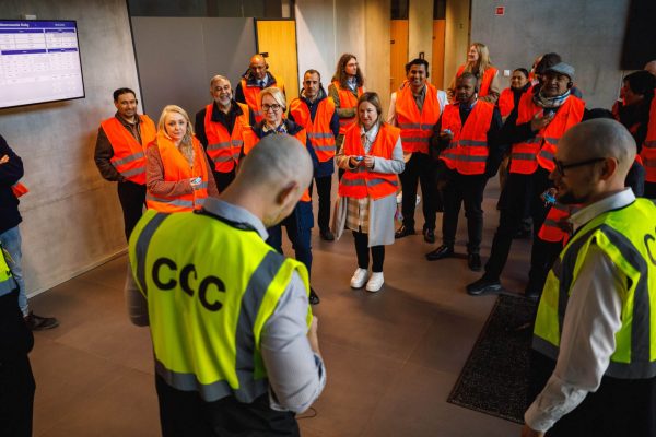 Pracownicy w kamizelkach CCC prowadzą odprawę dla grupy zwiedzających.