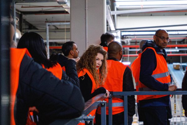 Zwiedzający stoją przy barierkach na metalowej platformie w magazynie.