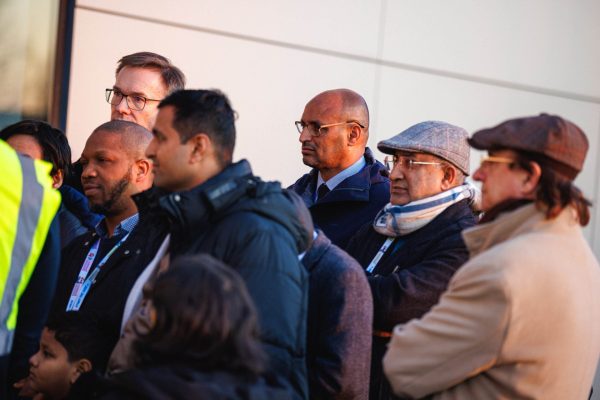 Grupa uczestników konferencji słucha przewodnika na zewnątrz obiektu.