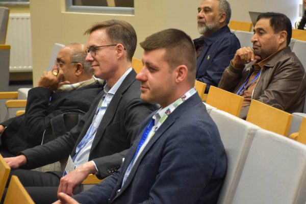 Uczestnicy konferencji siedzą w fotelach i słuchają wystąpienia.