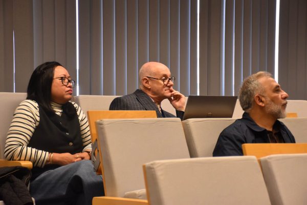 Troje uczestników konferencji siedzi przy oknach i słucha wystąpienia.
