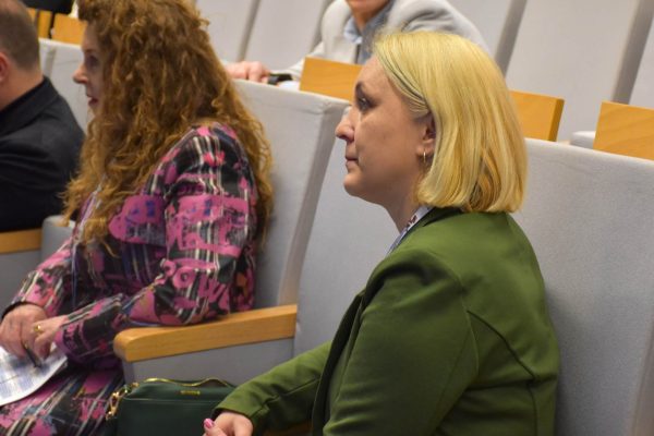 Dwie uczestniczki konferencji siedzą w fotelach, jedna w zielonym garniturze.