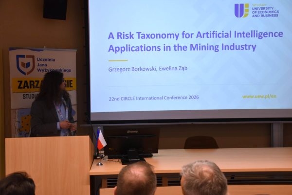 Prelegentka przy mównicy na tle tytułu prezentacji o ryzyku sztucznej inteligencji w górnictwie.