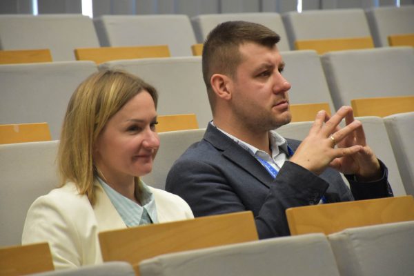 Kobieta i mężczyzna siedzą obok siebie, obserwując wystąpienie.