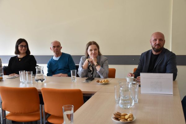 Czworo uczestników Klubu Absolwenta przy stole z wodą i poczęstunkiem.