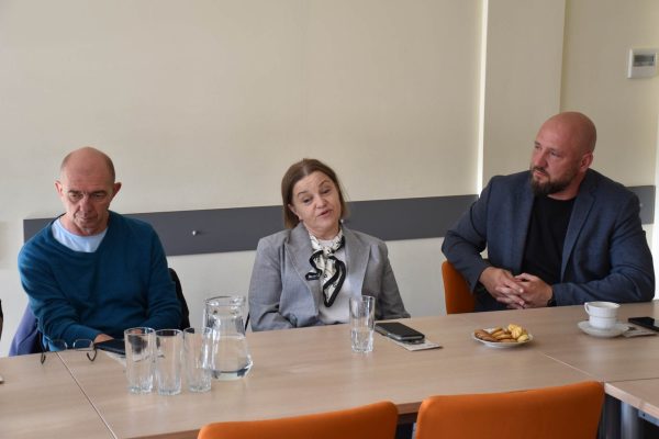 Troje uczestników Klubu Absolwenta rozmawia przy stole.