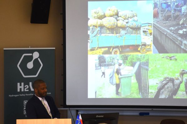 Prelegent przy mównicy omawia kolaż zdjęć dotyczących transportu i recyklingu.