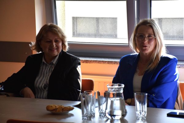 Dwie uczestniczki Klubu Absolwenta siedzą przy oknie, jedna w niebieskiej marynarce.