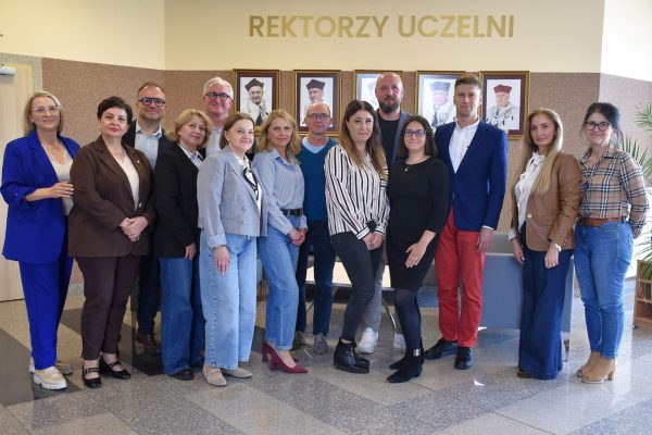 Grupowe zdjęcie uczestników Klubu Absolwenta pod portretami rektorów UJW.