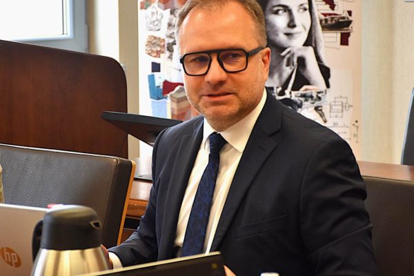 Uczestnik II Posiedzenia Rady Dyrektorów UJW siedzi przy stole z laptopem.