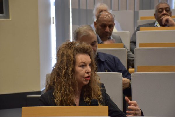 Uczestniczka z kręconymi włosami gestykuluje podczas wypowiedzi na widowni.
