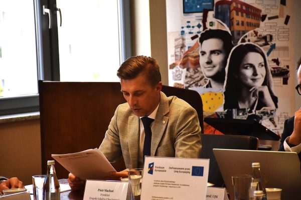 Uczestnik posiedzenia w jasnej marynarce czyta dokumenty.