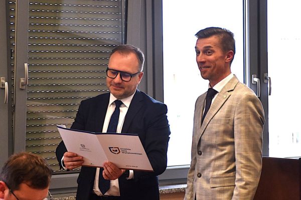Dwaj przedstawiciele uczelni prezentują dokument podczas posiedzenia Rady Dyrektorów.