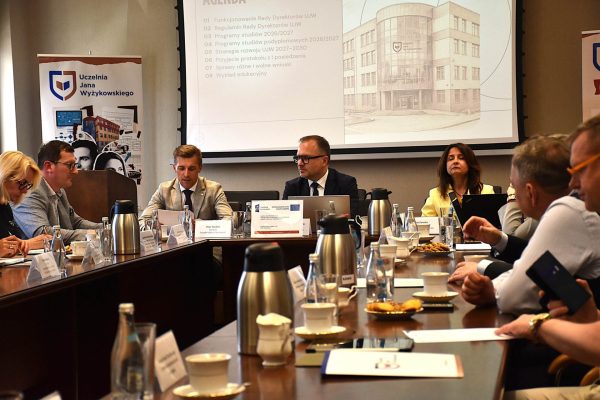 Widok posiedzenia Rady Dyrektorów ze stołem konferencyjnym i ekranem prezentacji.