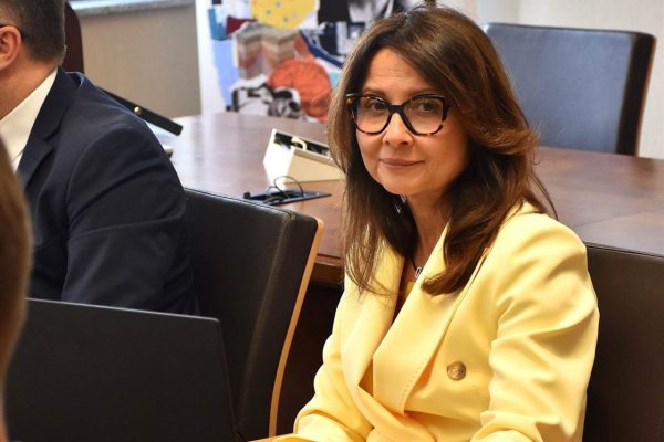 Uczestniczka w żółtej marynarce siedzi przy stole podczas obrad.