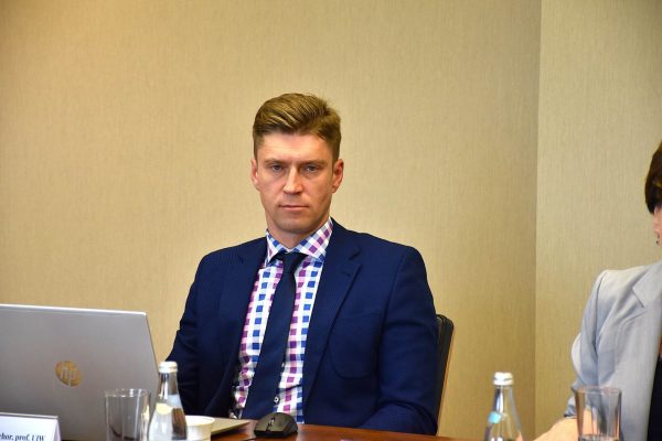 Uczestnik w granatowej marynarce siedzi przy otwartym laptopie.