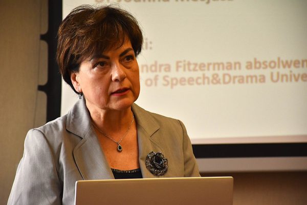 Zbliżenie na prelegentkę słuchającą pytania przy laptopie.