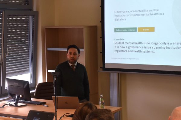 Prelegent przedstawia temat opieki nad studentami i zdrowia psychicznego w szkolnictwie wyższym.
