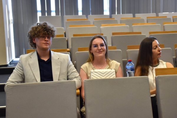 Troje młodych uczestników konferencji siedzi na widowni.